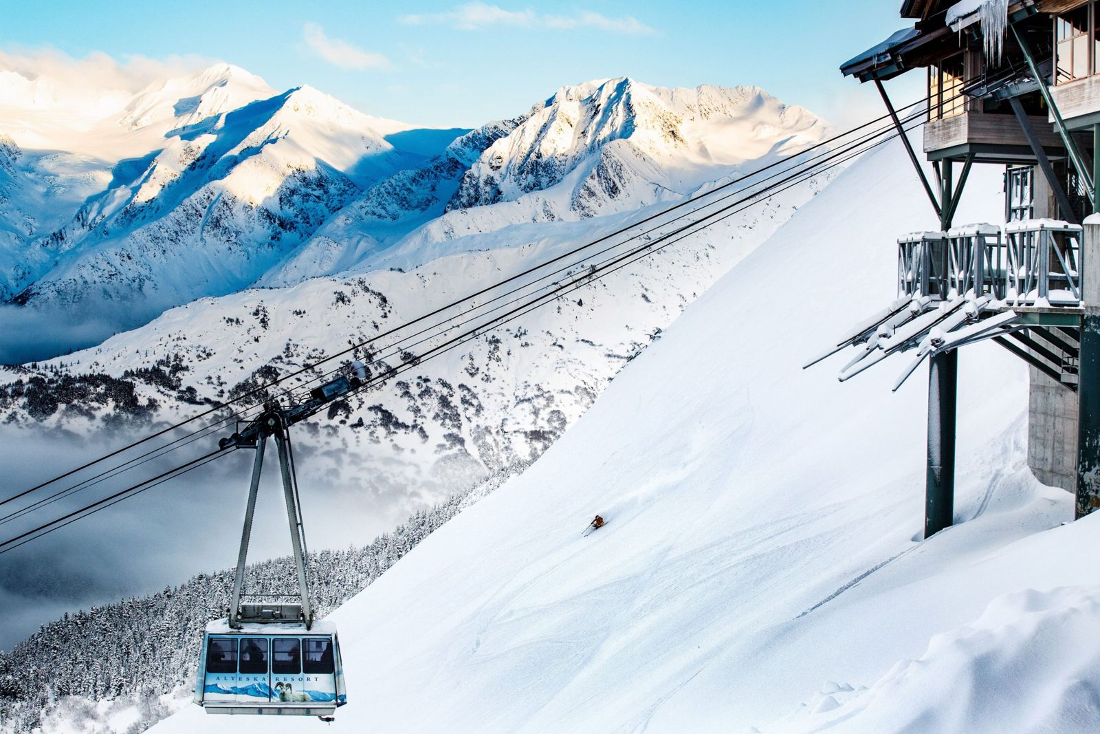 The aerial tram at Alyeska Resort climbing above snowy slopes, with Turnagain Arm and mountains beyond