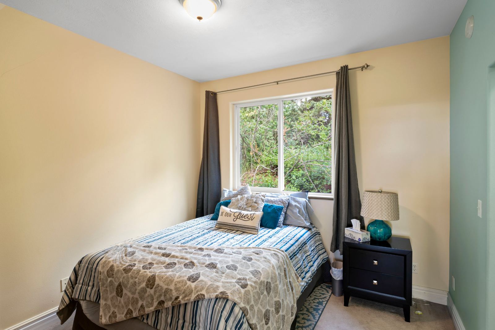 Bedroom with a full bed and a window onto trees