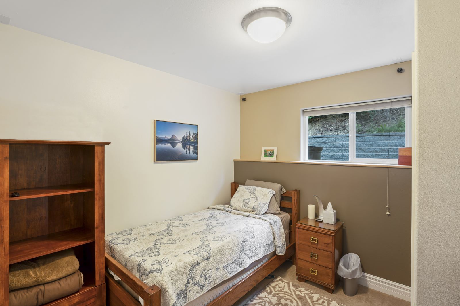Lower-level bedroom with a twin bed and bookshelf