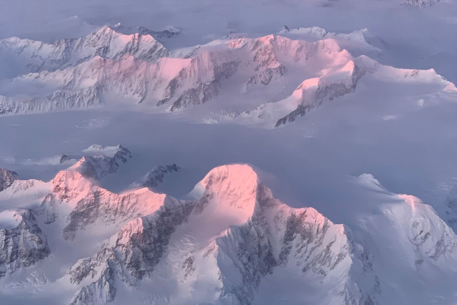 Snow-covered peaks of the Chugach Mountains in pink winter light, seen from the air