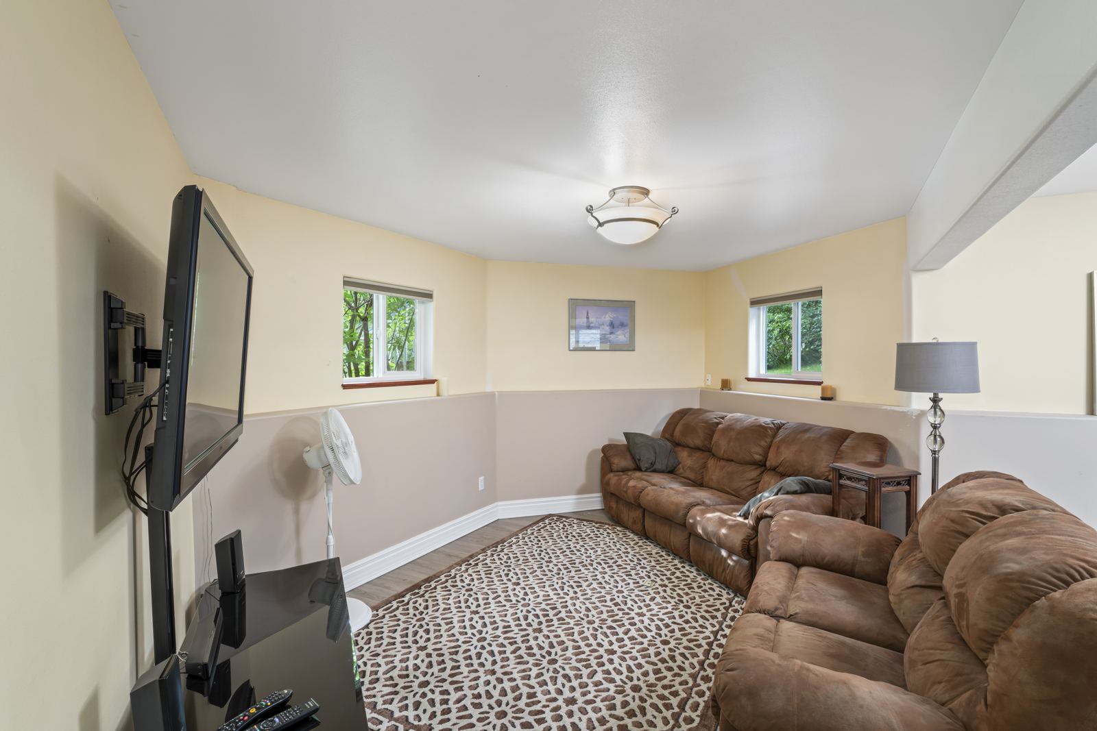 Downstairs TV room with a brown reclining sectional and wall-mounted TV
