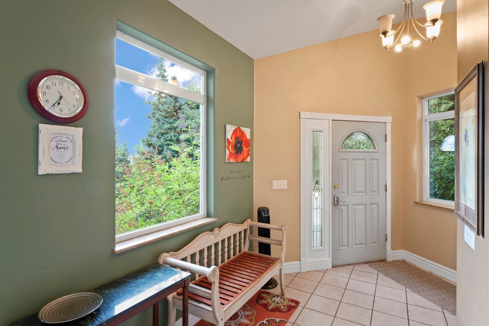 Tiled entryway with a bench and a large window
