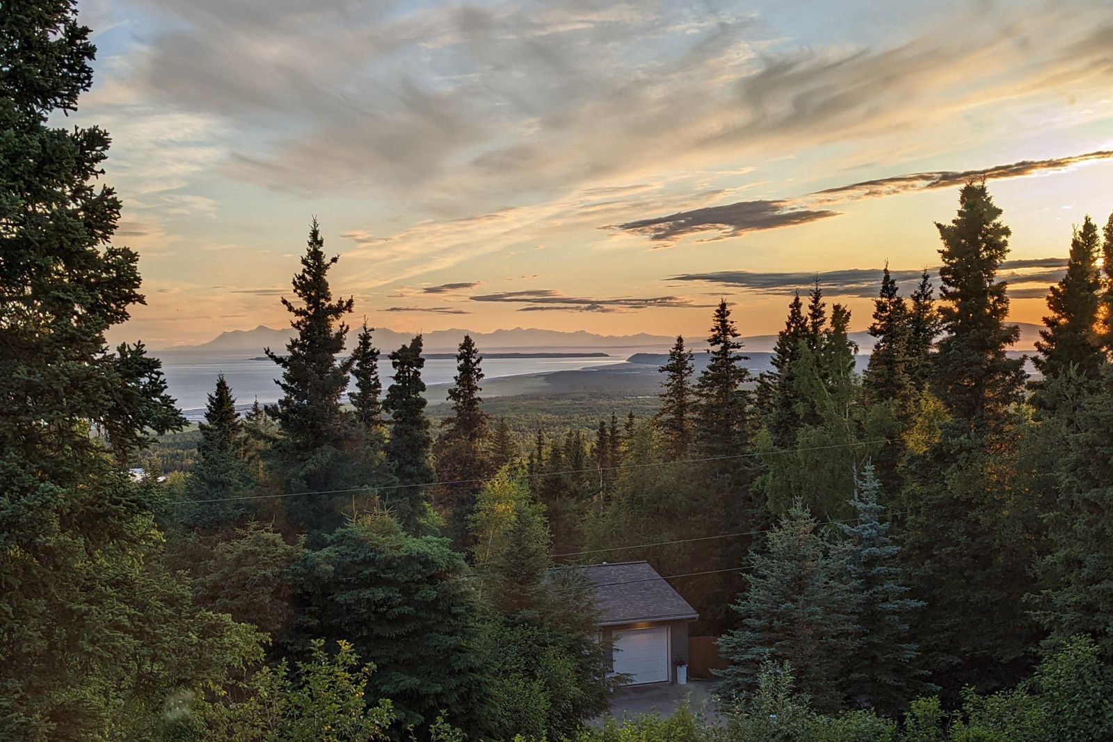Golden evening light over Cook Inlet and the spruce forest below the house