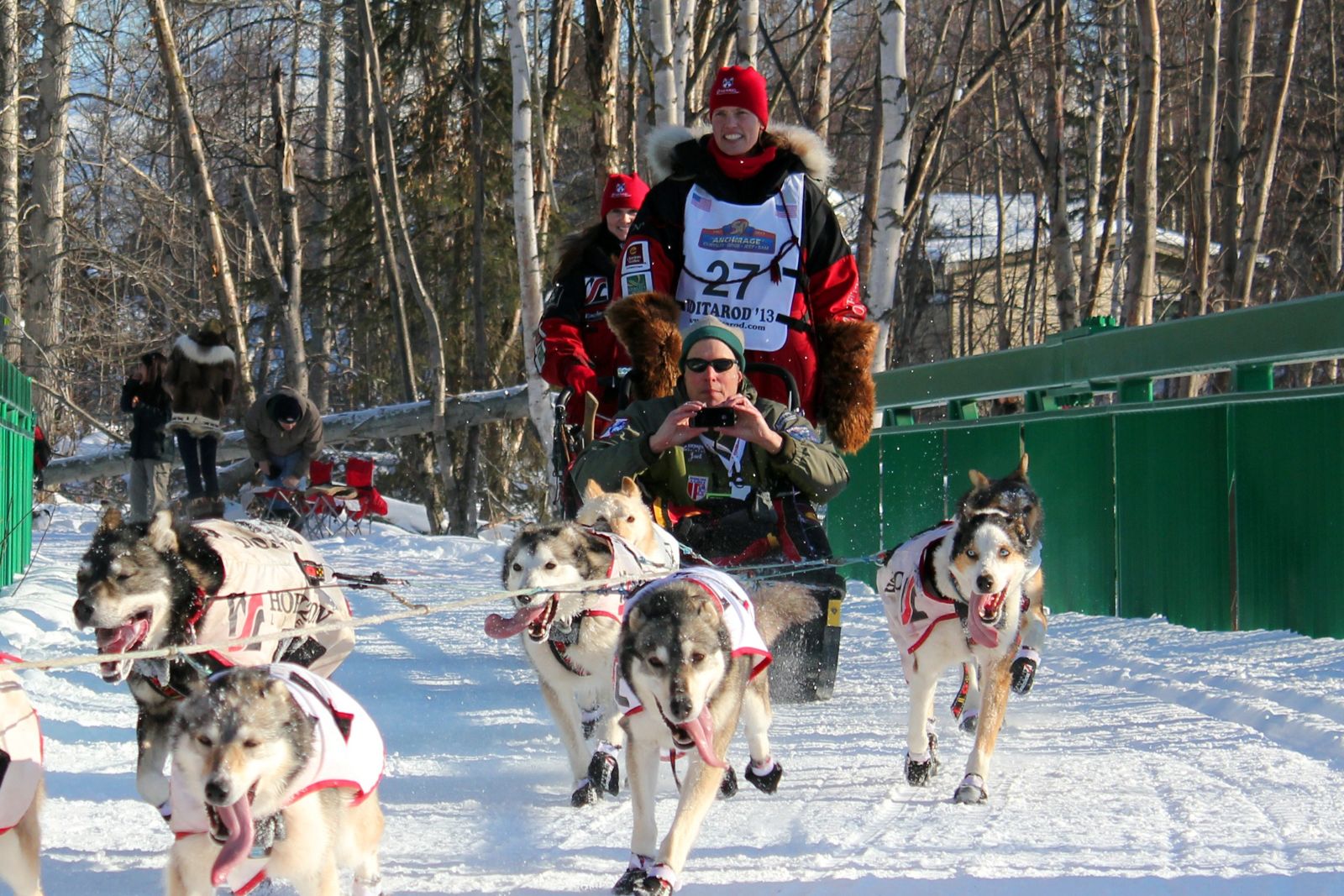 An Iditarod musher and dog team running through snow at the ceremonial start in Anchorage