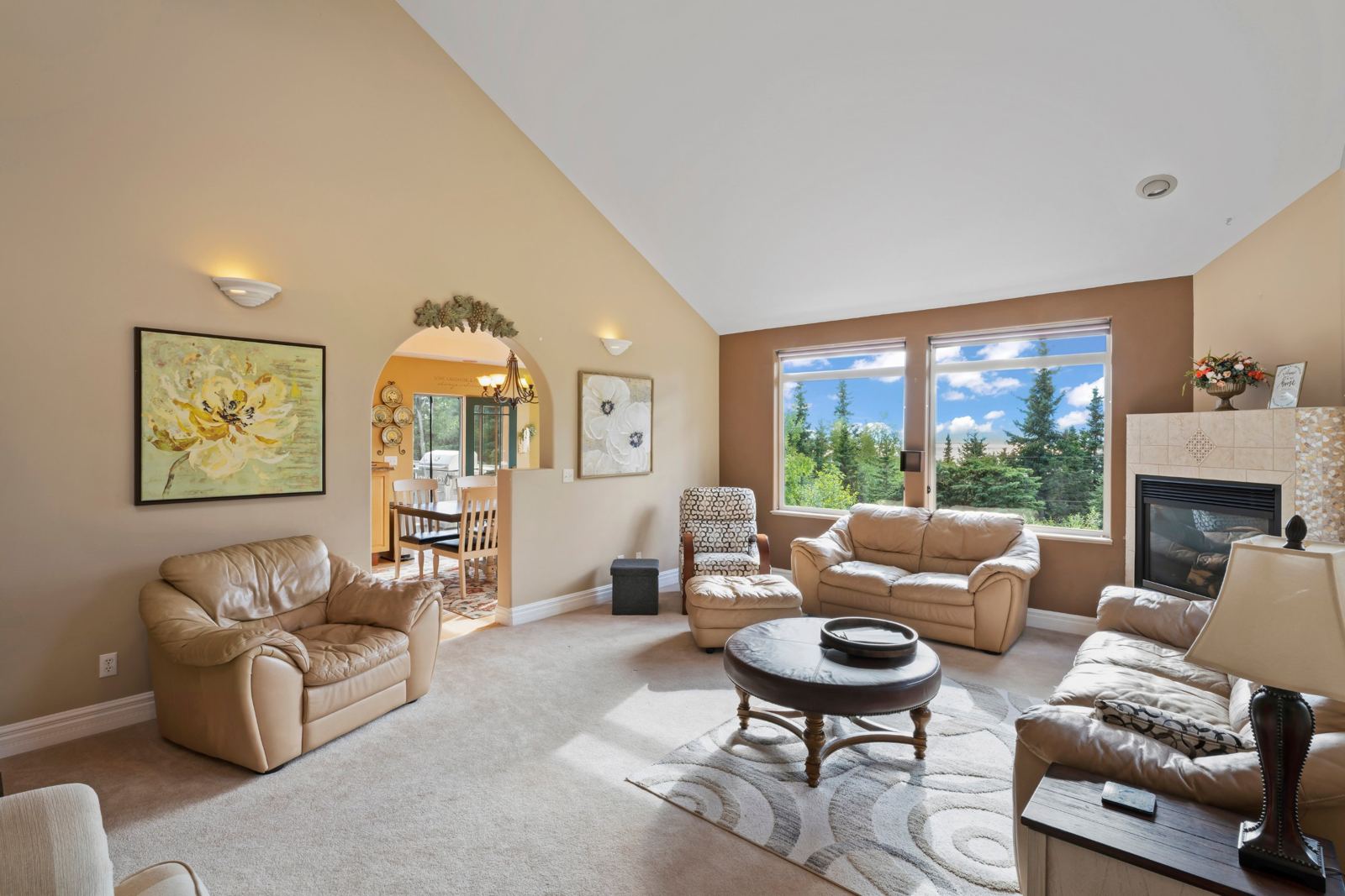 Vaulted living room with leather seating and an arched opening to the dining room