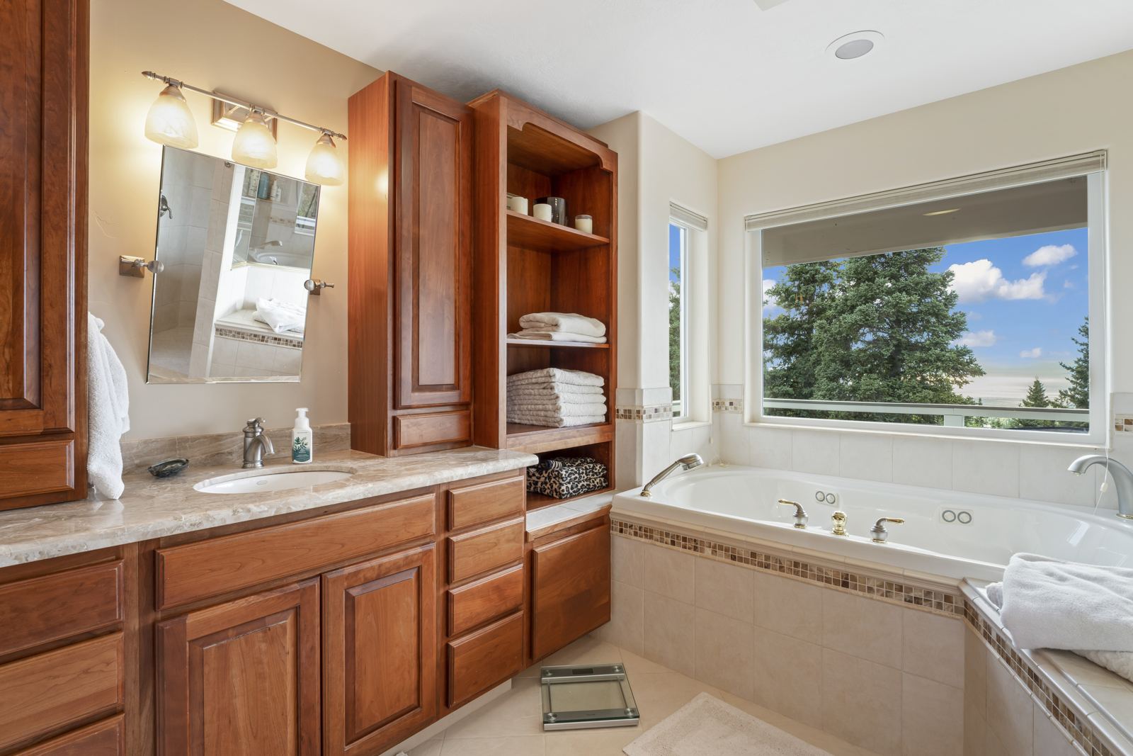 Primary bathroom with a jetted tub beneath a large window