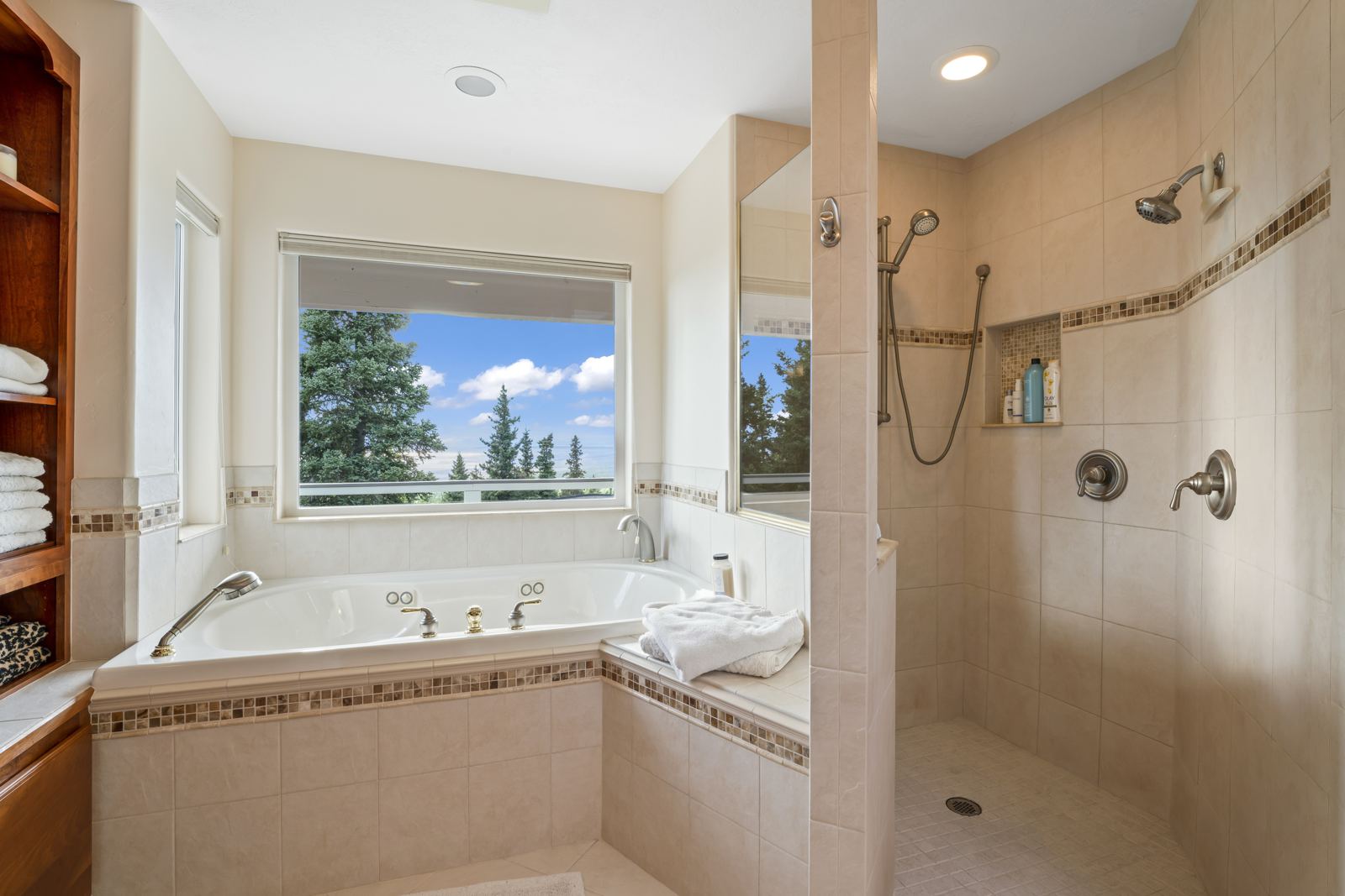 Jetted tub beside a tiled walk-in shower with two shower heads