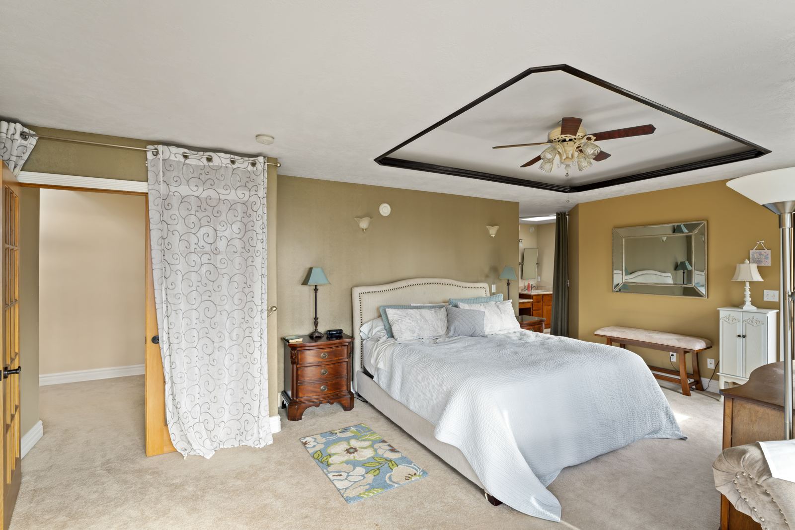 Primary suite bedroom with a tray ceiling and ceiling fan